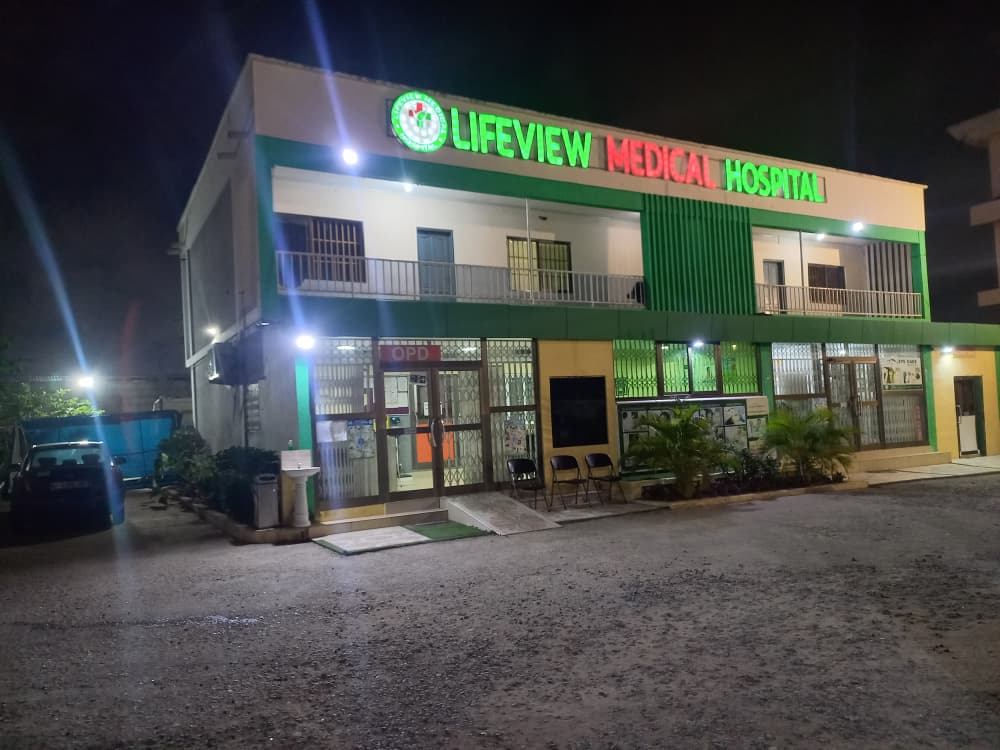 Lifeview Medical Hospital at night, with its lit green and red sign above the OPD entrance